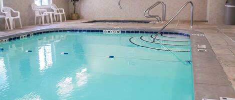Una piscina interior con marcas de carril claras, un elevador de piscina y un cartel que indica la zona de la piscina.