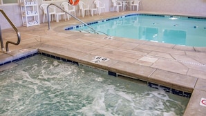 Una piscina interior con solárium de azulejos, tumbonas y un flotador.