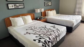 A hotel room with two beds, a nightstand with a lamp, and framed pictures on the wall.