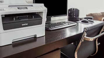 A desk with a Brother printer, a laptop, a keyboard, a mouse, and a black chair.