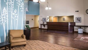 Un vestíbulo de hotel con una recepción, un sofá y una alfombra estampada.
