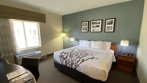 Habitación de hotel con una cama grande, dos mesitas de noche con lámparas, un escritorio y una silla. Hay tres cuadros enmarcados en la pared.
