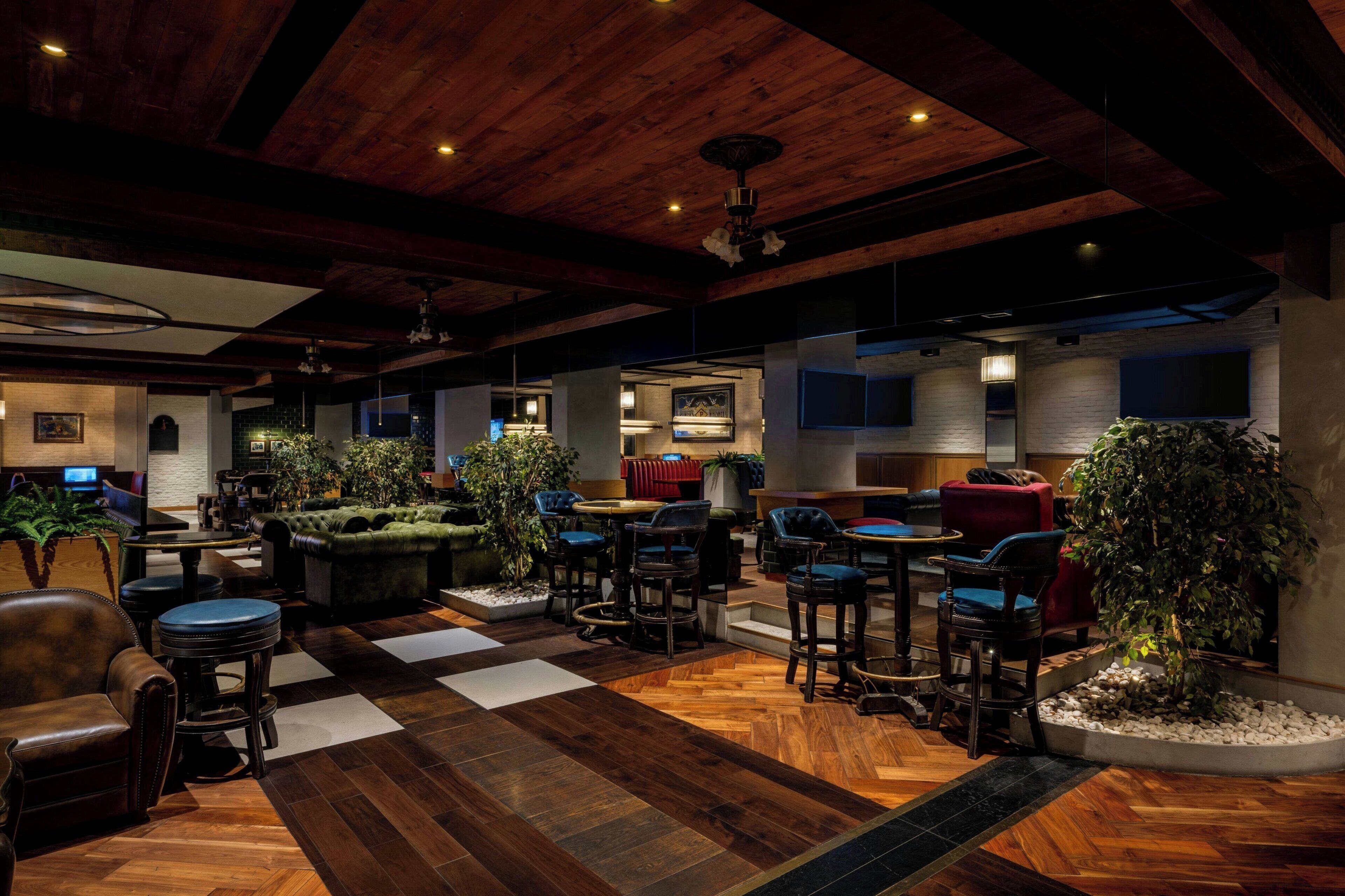 A spacious lobby with a wooden floor, multiple seating areas, and a television mounted on the wall.