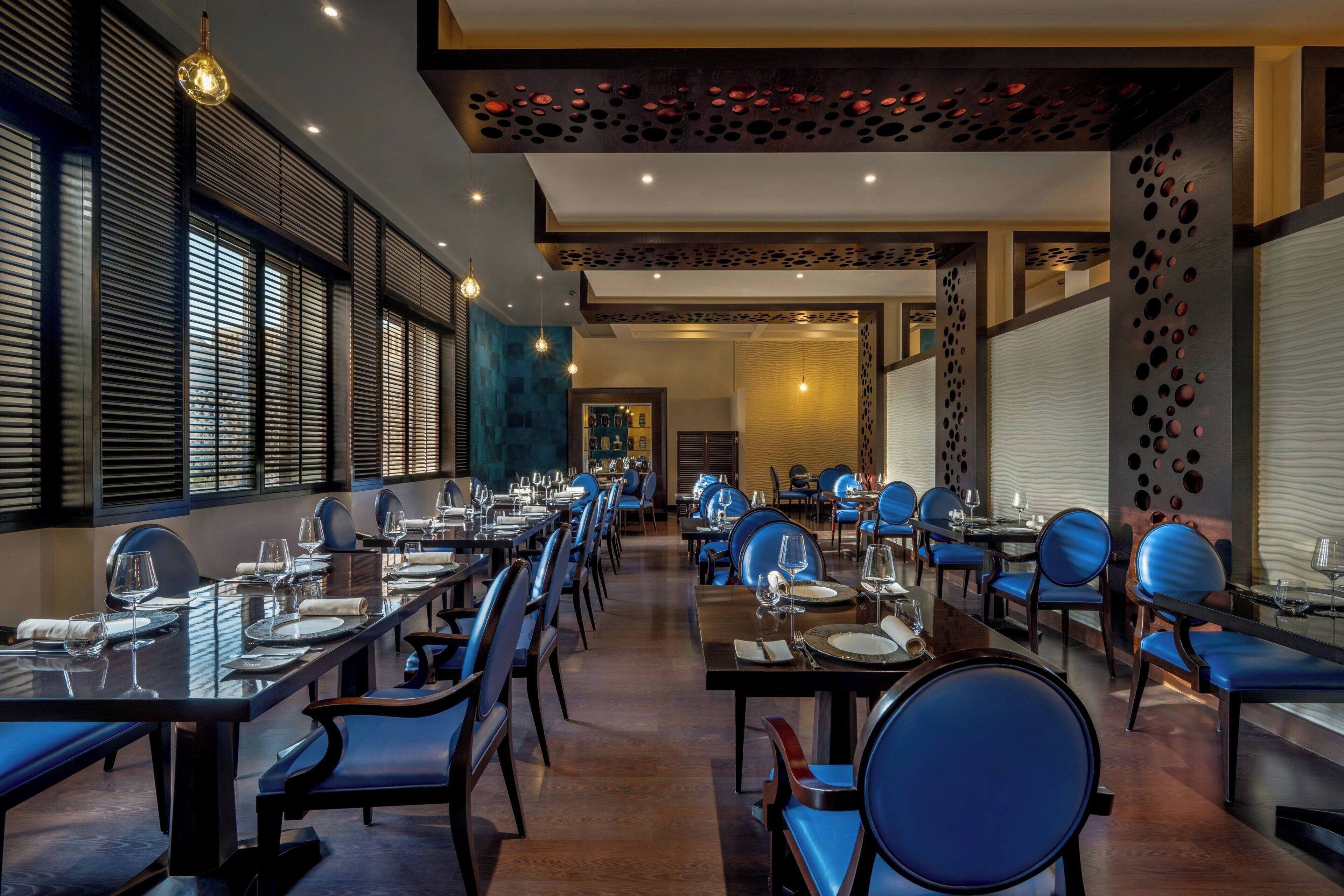 A restaurant with long tables, blue chairs, and a modern interior design.