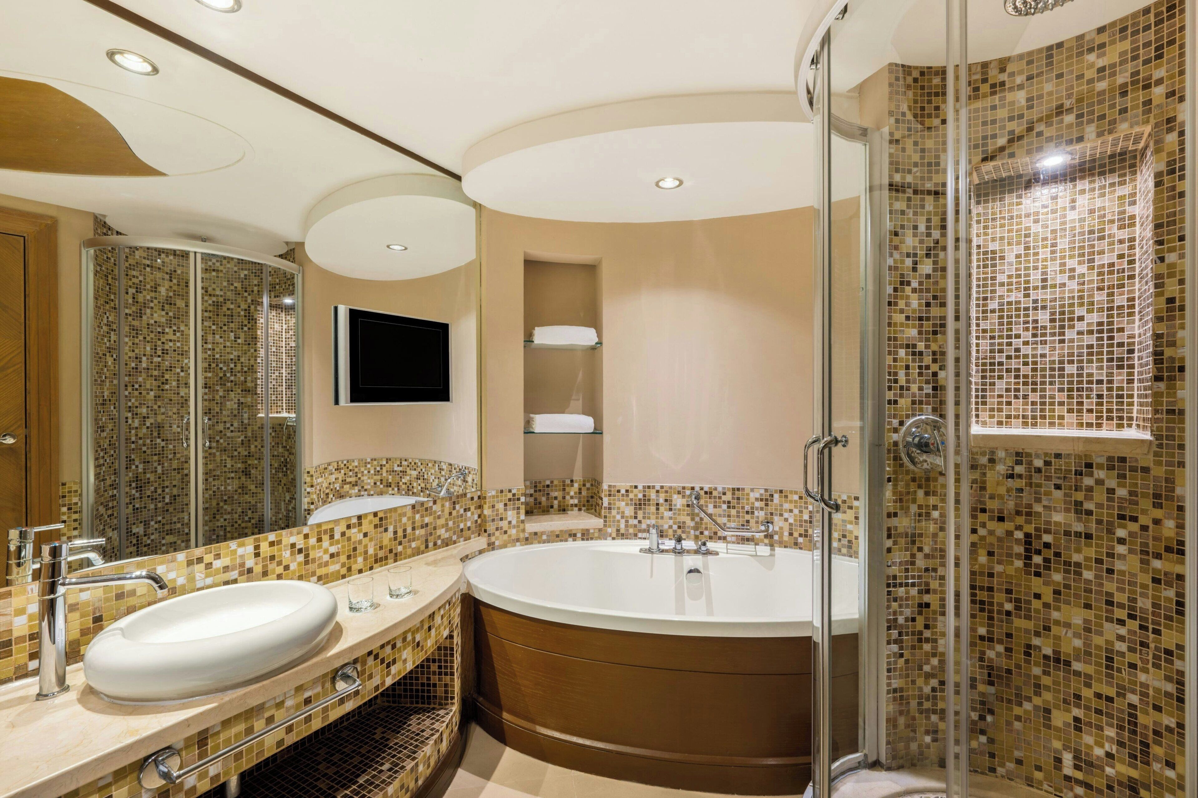 Un baño moderno con una bañera grande, una ducha con cerramiento de vidrio y un lavamanos con lavabo y espejo.