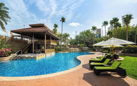 A swimming pool with lounge chairs and a covered area.