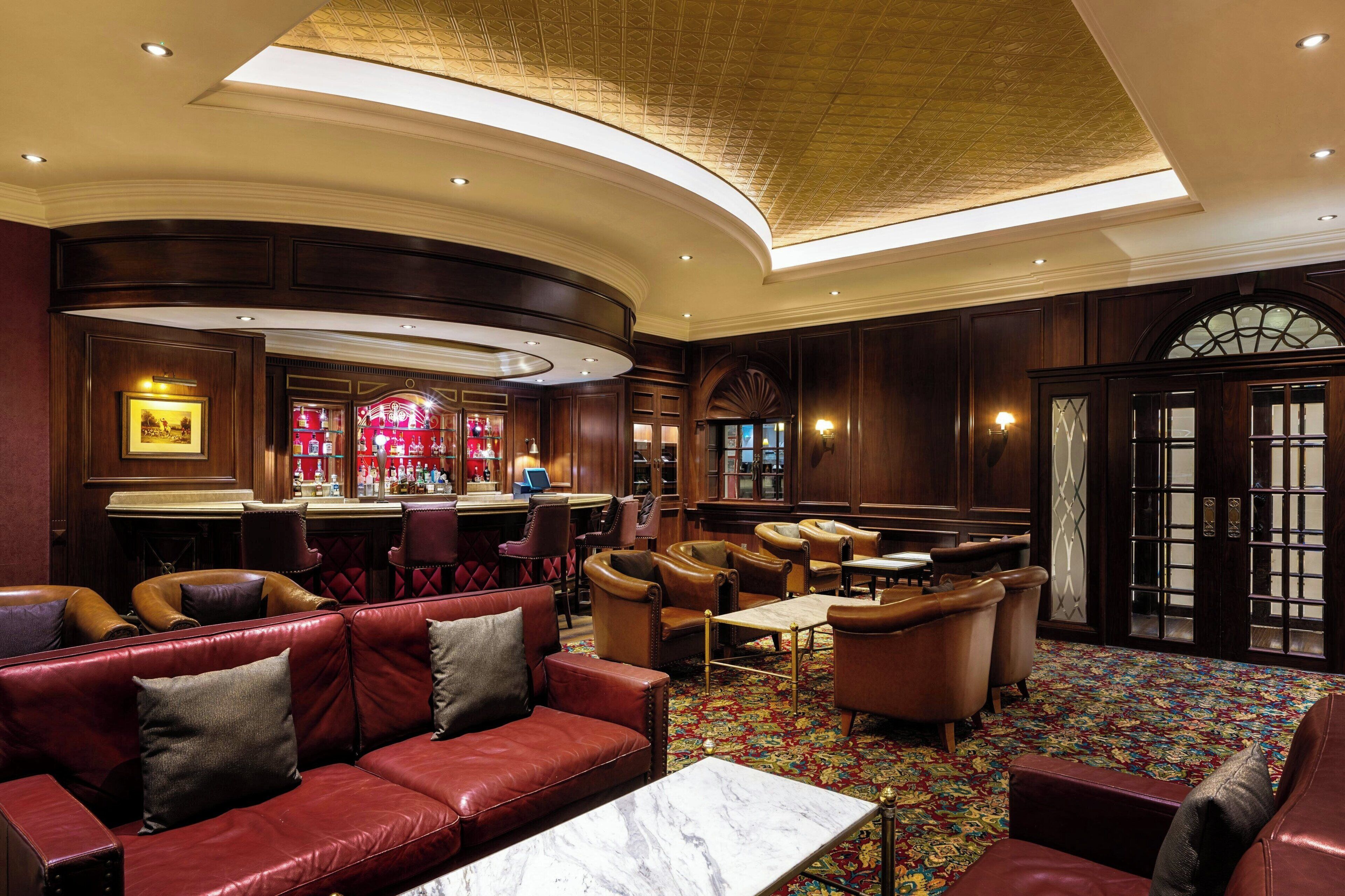 A spacious lobby with leather seating, a bar area, and a patterned carpet.