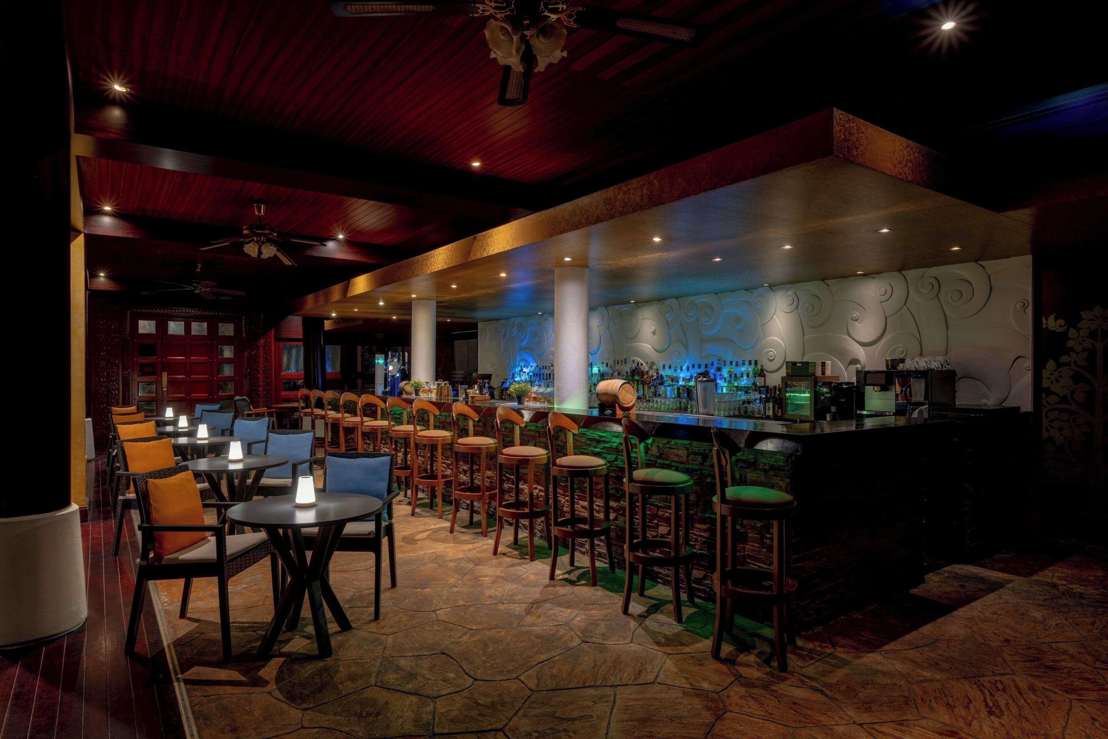 Eine Bar mit mehreren Sitzhocker und Tischen, einer Theke mit Barbistro-Ausrüstung und einer Wand mit wirbelnden Mustern.