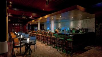A bar area with multiple stools and tables, a counter with bar equipment, and a decorative wall with swirling patterns.