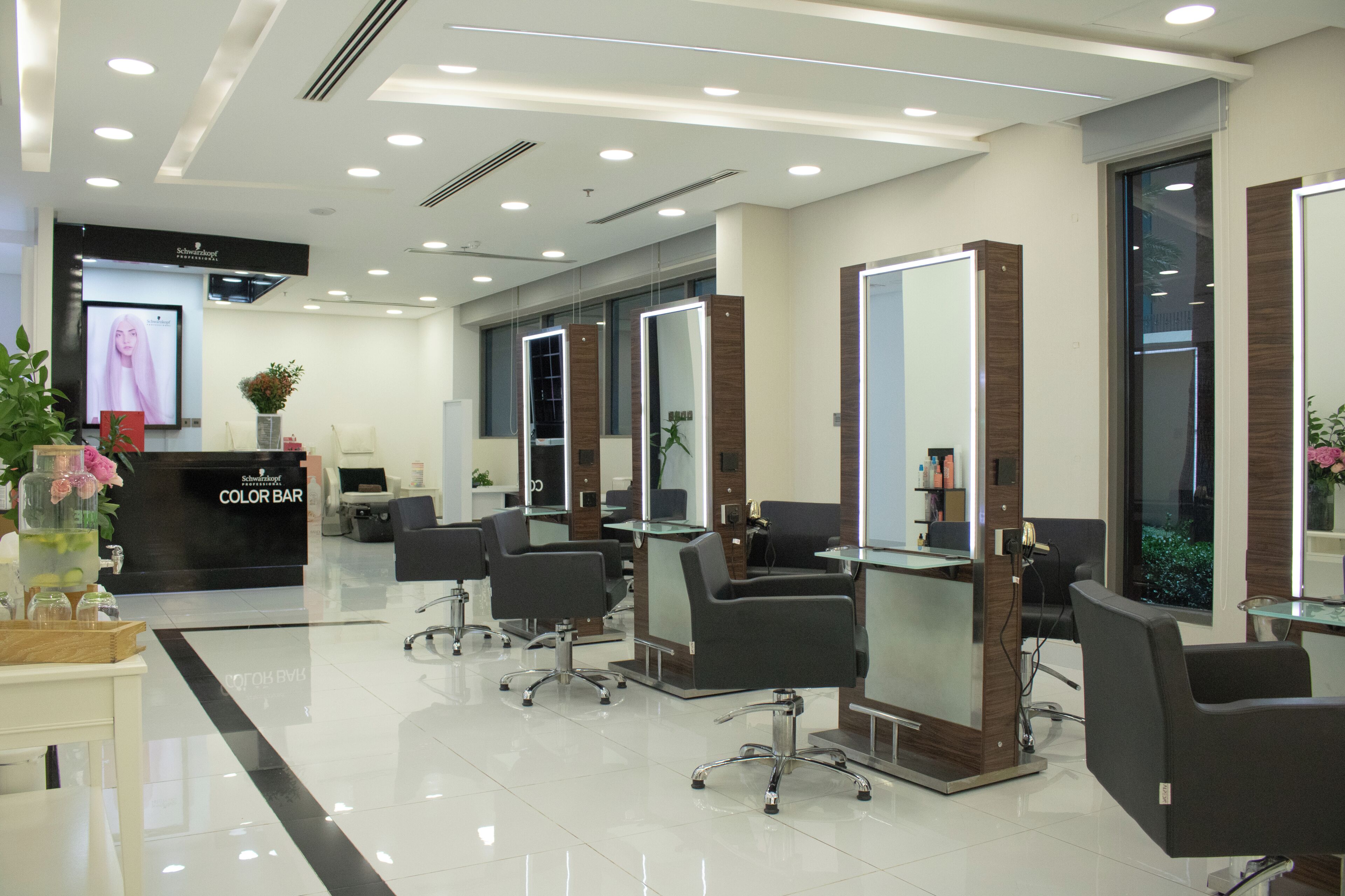 A modern hair salon with multiple stations, a reception desk, and a color bar area.