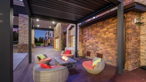 An outdoor patio with wicker furniture and a fire feature, surrounded by stone walls. - The Leo Collection Detroit, an Ascend Collection Hotel (Lincoln Park)