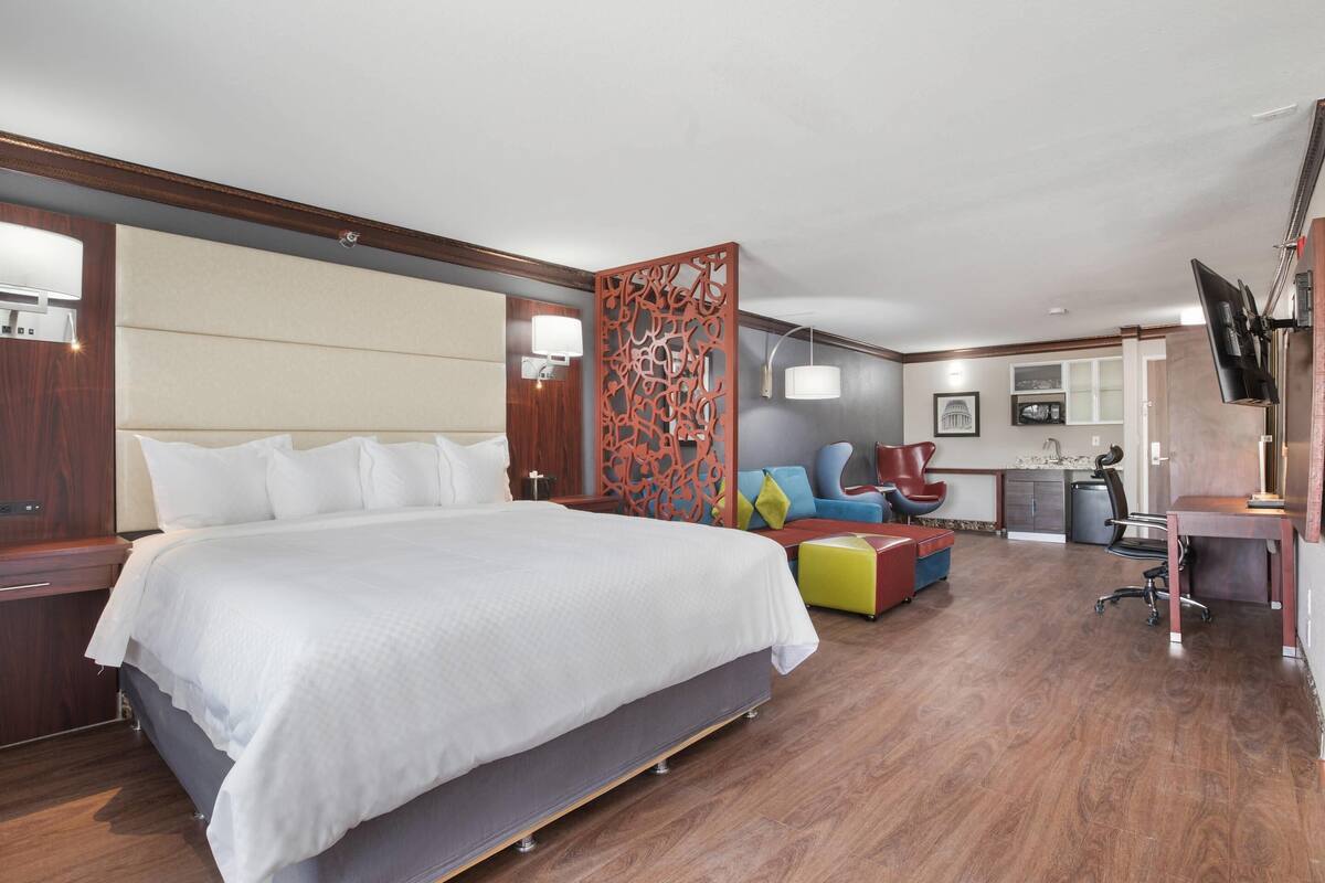 A modern hotel room with a large bed, a desk, a chair, and a TV.