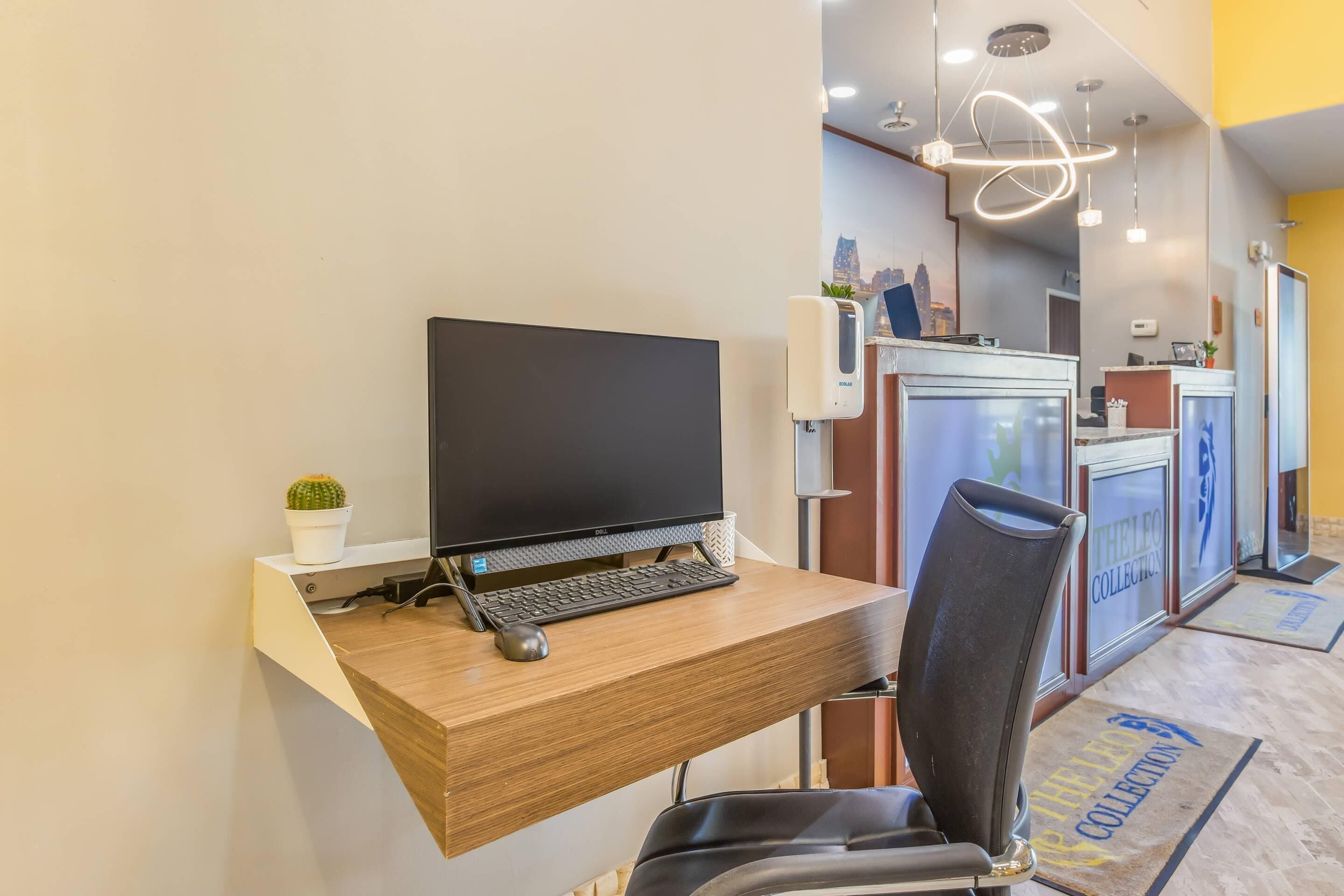 Un comptoir d’accueil avec un ordinateur, une chaise et une plante en pot.