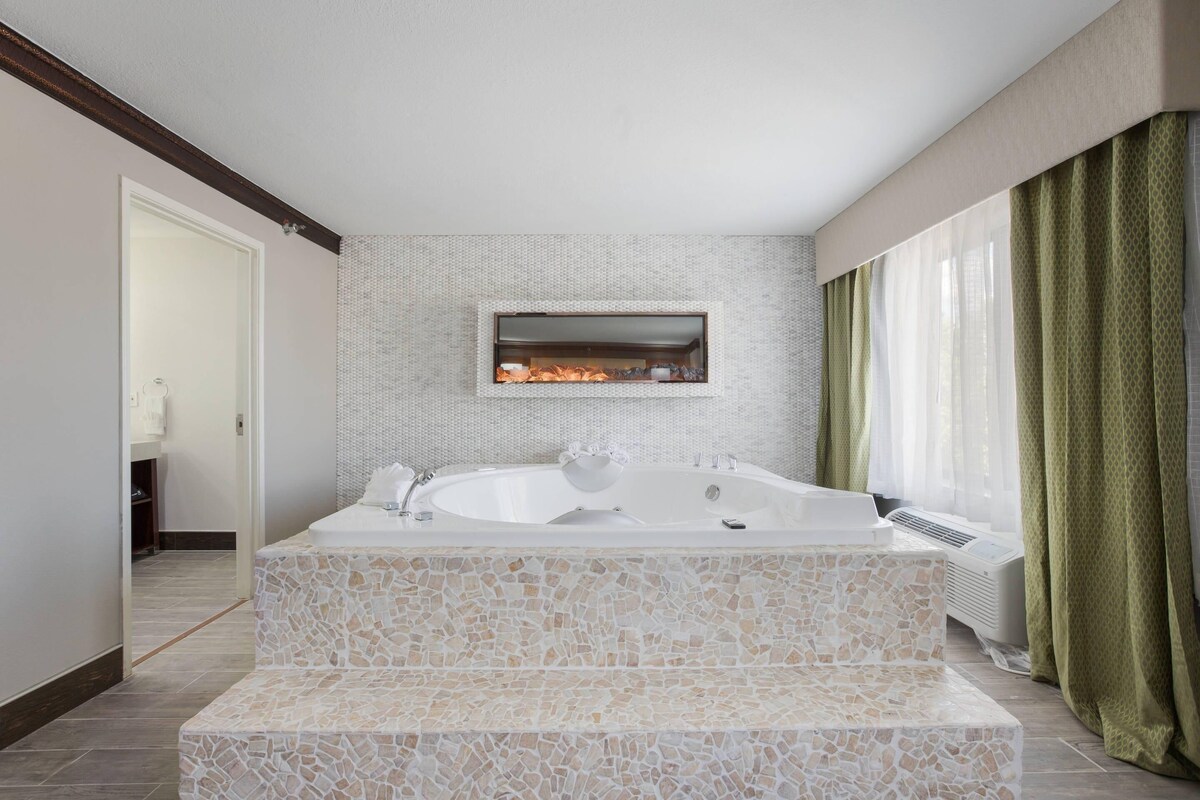 Un baño moderno con una bañera independiente, ducha integrada y diseño de mosaicos.