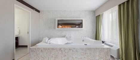 Een moderne badkamer met een vrijstaand bad, een inloopdouche en een mozaïek tegel ontwerp.