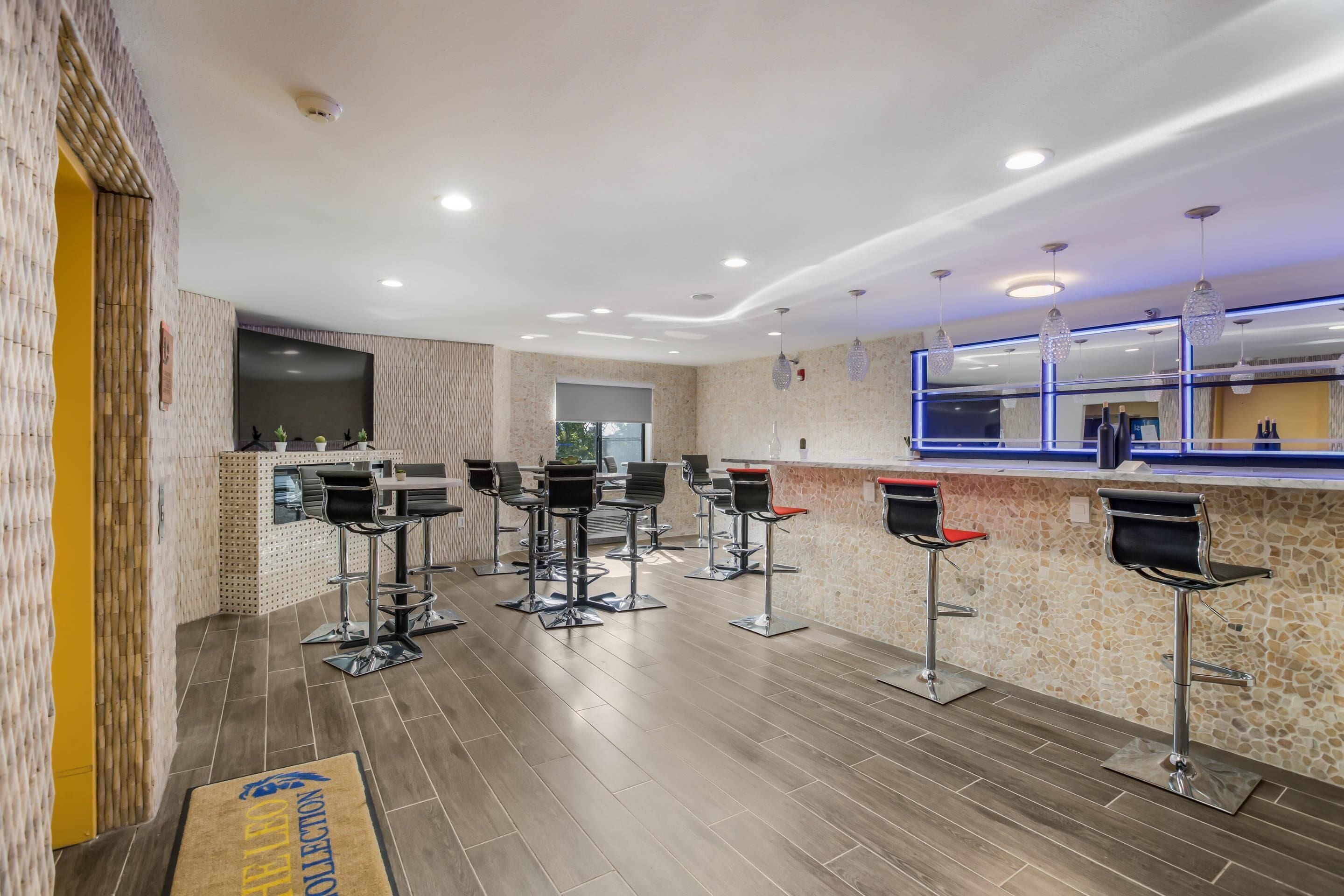 A modern bar area with multiple stools, a counter, and a large TV screen.