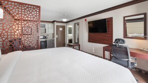 A hotel room with a large bed, a desk with a chair, a TV mounted on the wall, and a bathroom visible through an open door. - The Leo Collection Detroit, an Ascend Collection Hotel (Lincoln Park)