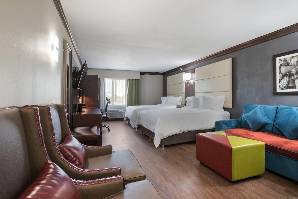 A hotel room with a large bed, a sofa, a chair, and a desk.