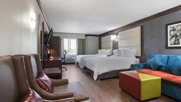 Una camera d'albergo con un letto grande, un divano, una poltrona e una scrivania.