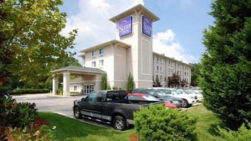 A Sleep Inn hotel with a parking lot, a covered entrance, and a well-maintained lawn.