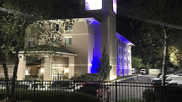 A building with a prominent clock tower, a gated entrance, and a parking area with several cars. - Sleep Inn Raleigh Durham Airport (Durham)