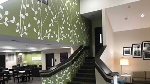A modern hotel lobby with a staircase, seating area, and artwork on the walls. - Sleep Inn Raleigh Durham Airport (Durham)
