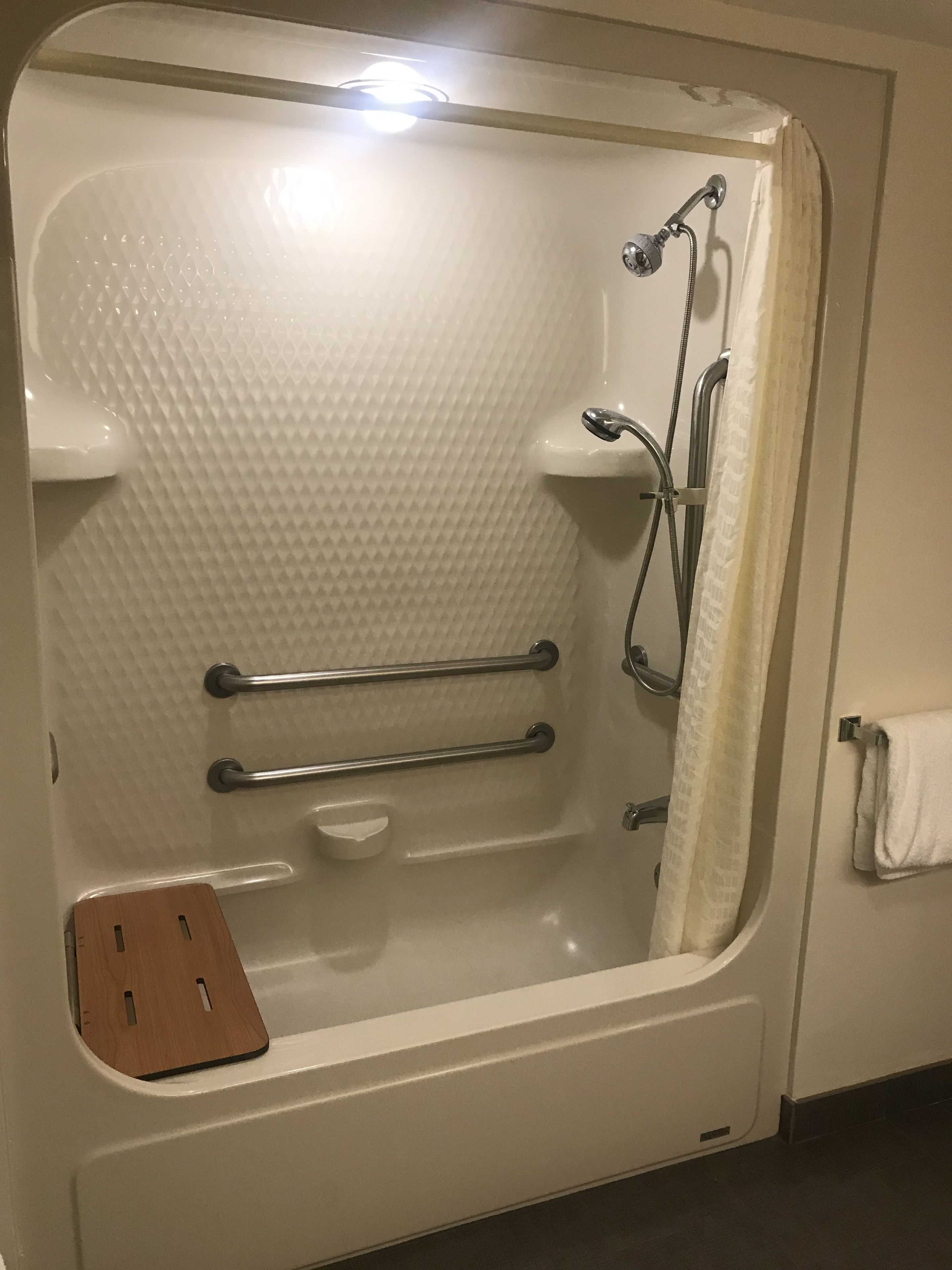 Una bañera con ducha, un perchero y una bandeja de madera.