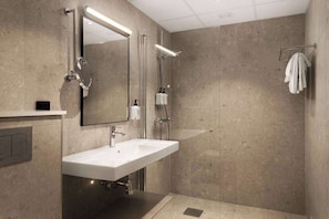 Un baño moderno con un espejo grande, un lavamanos y una zona de ducha.