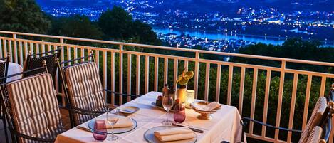 A table set for dining with a view of a cityscape at dusk.