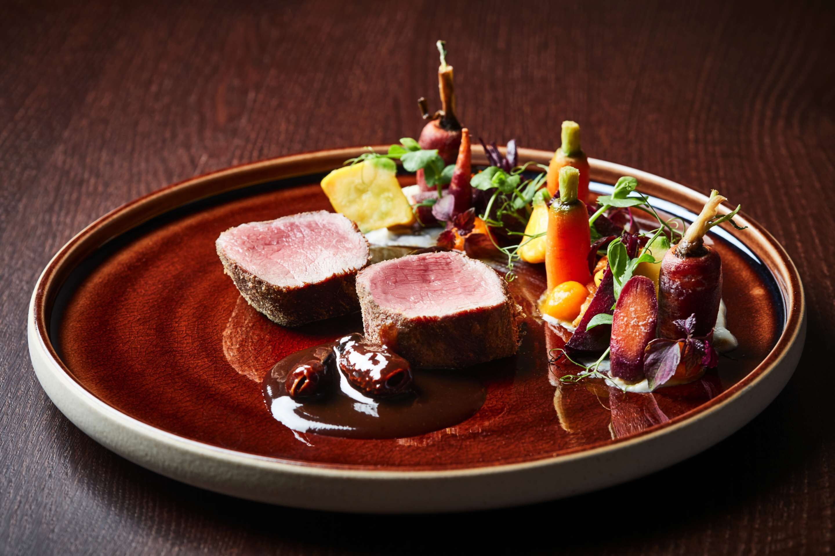 A plate with sliced meat, vegetables, and a sauce.