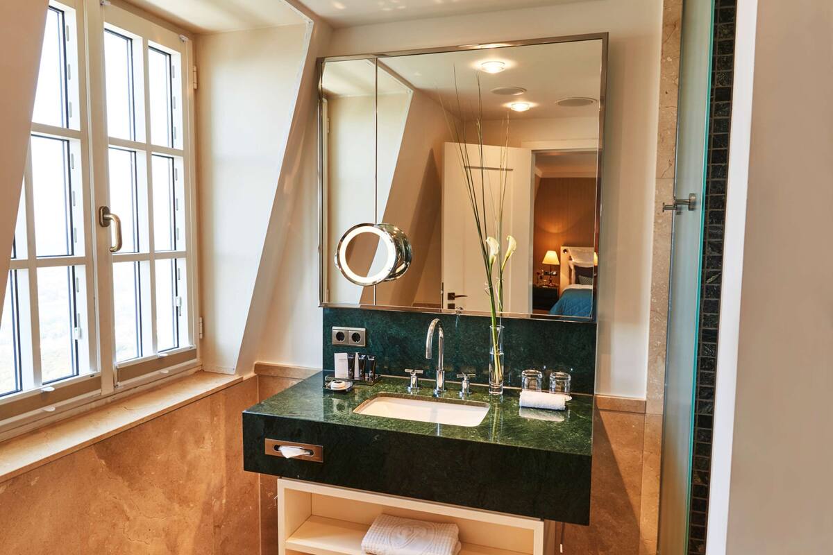 A modern bathroom with a large mirror, a sink, and a window.