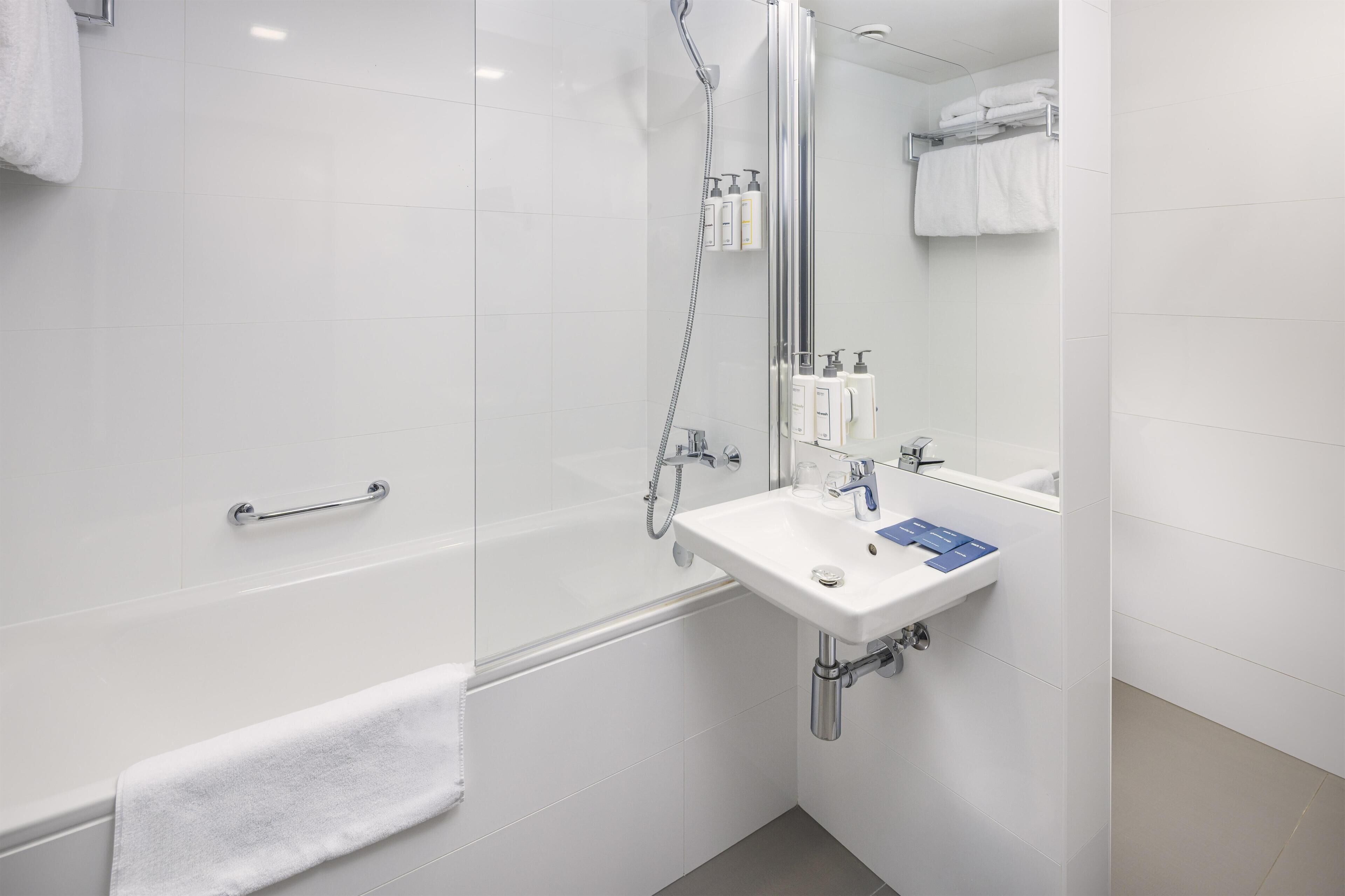 Een moderne badkamer met een douchecabine, een wit wastafelmeubel met spiegel, en een handdoekrek.