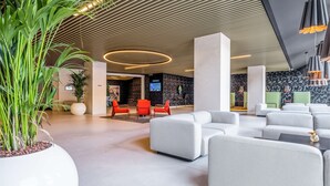 A modern lobby with a high ceiling, large potted plants, and a seating area with white sofas. - Park Inn by Radisson Danube Bratislava (Bratislava)