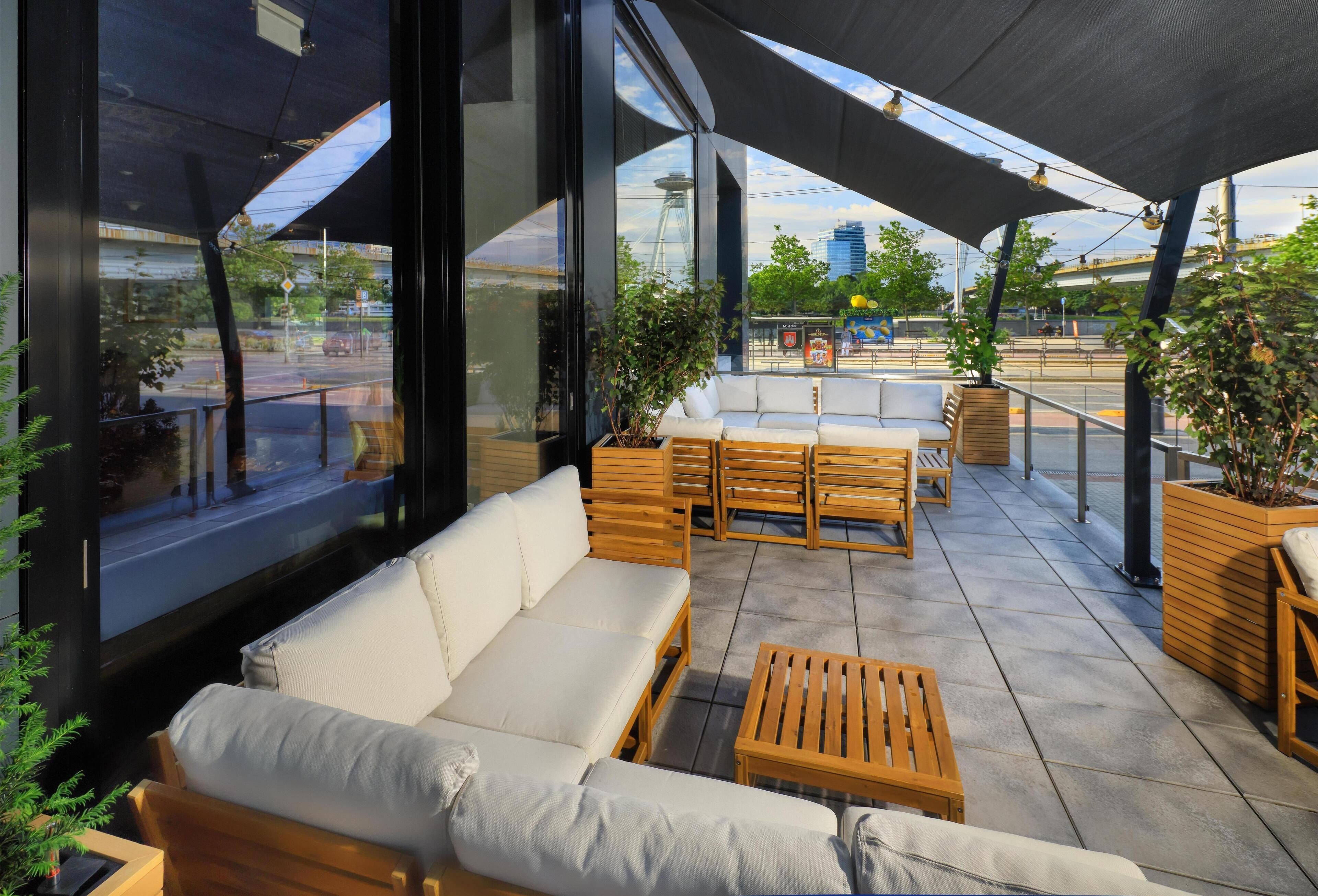 An outdoor seating area with a sofa, wooden chairs, and a table.