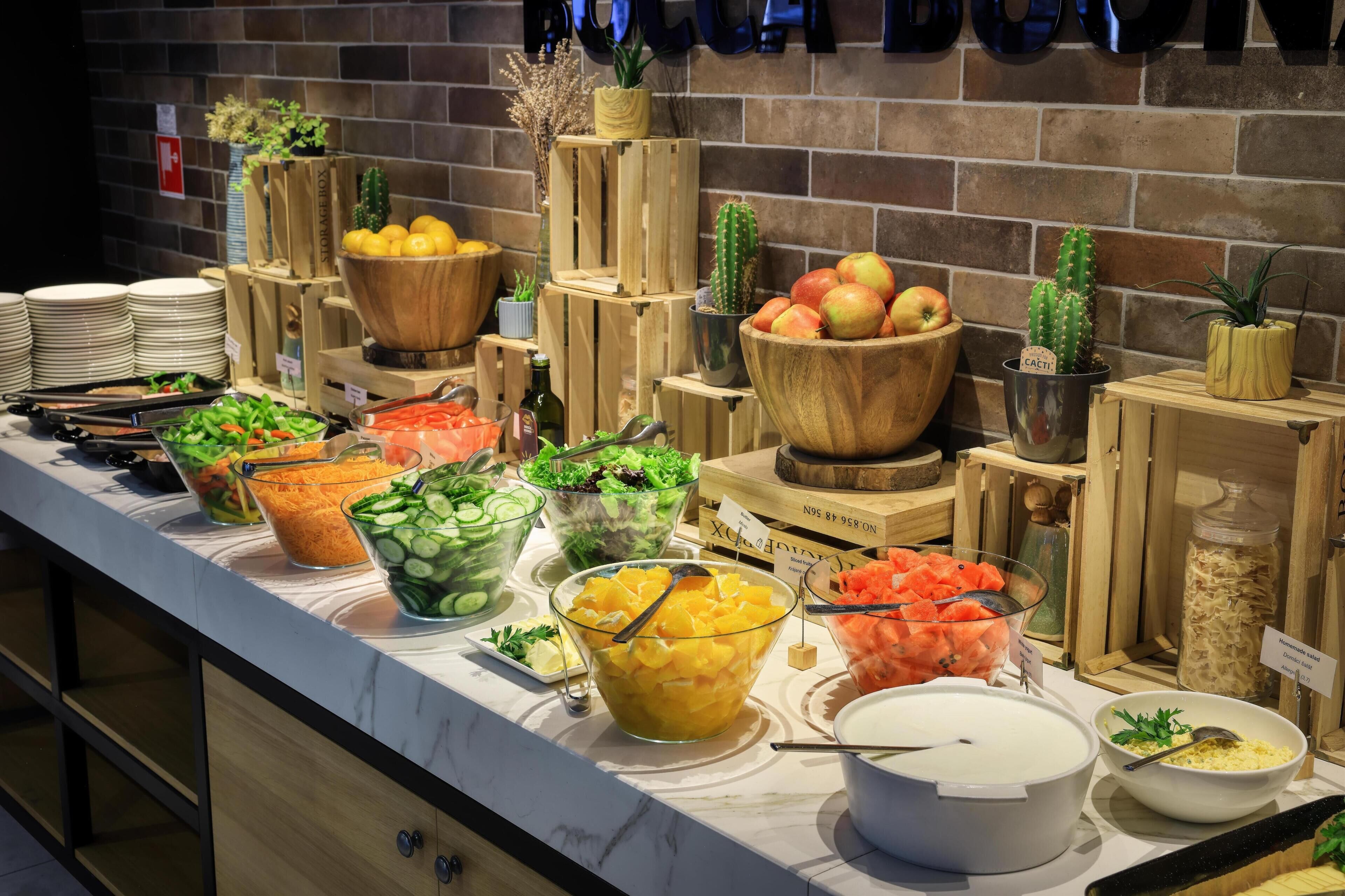A buffet with various food items and a brick wall background.