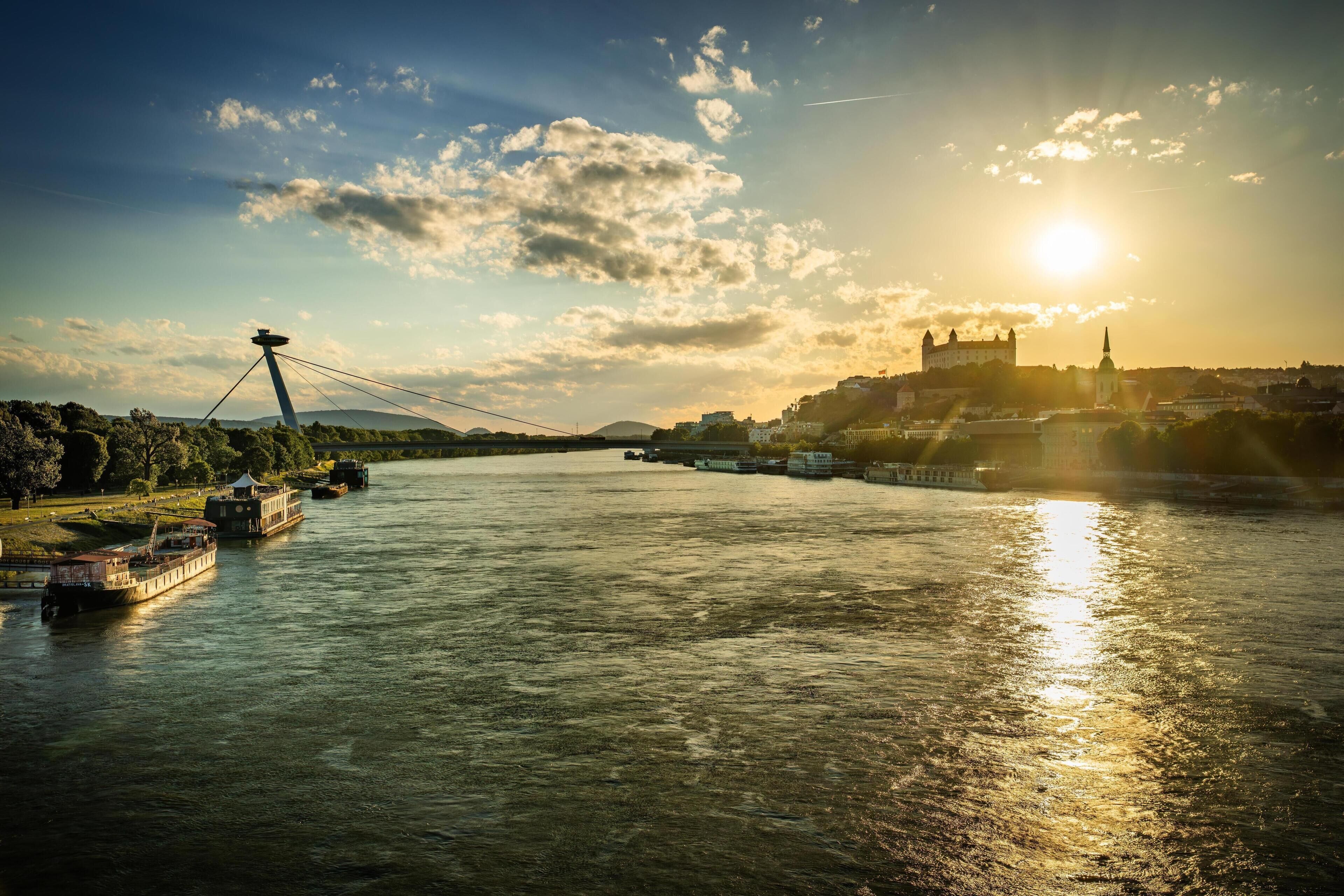 A river with boats, a bridge, and a castle in the background.