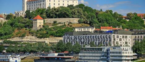 A historic castle on a hill with a river in the foreground.
