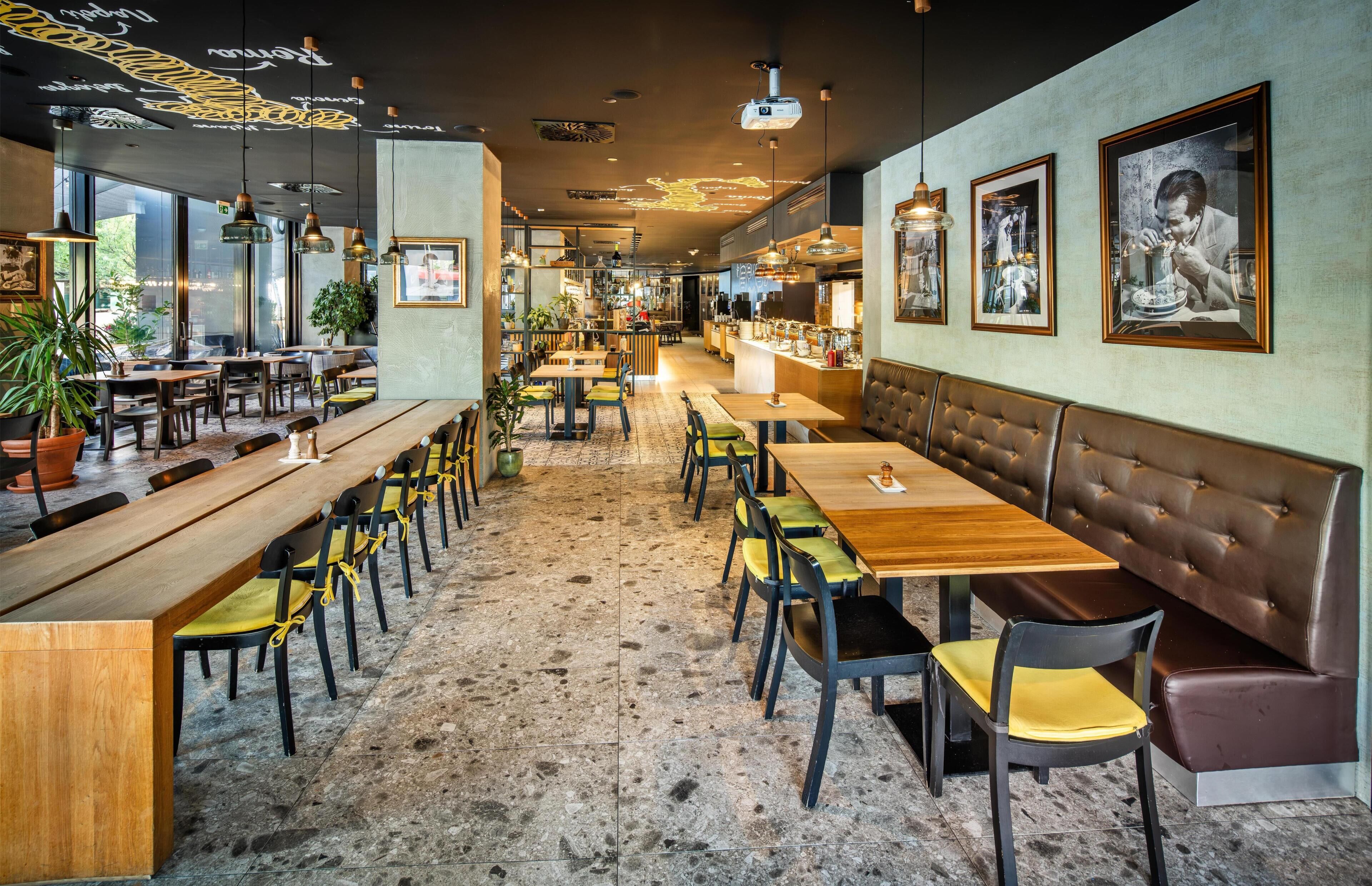 A restaurant interior with wooden tables, chairs, and a bar area.