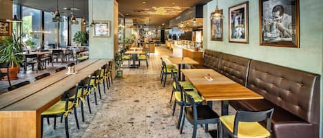 A restaurant interior with wooden tables, chairs, and a bar area.