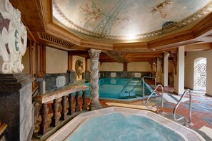 Una piscina interior con techo de madera y columnas de piedra.