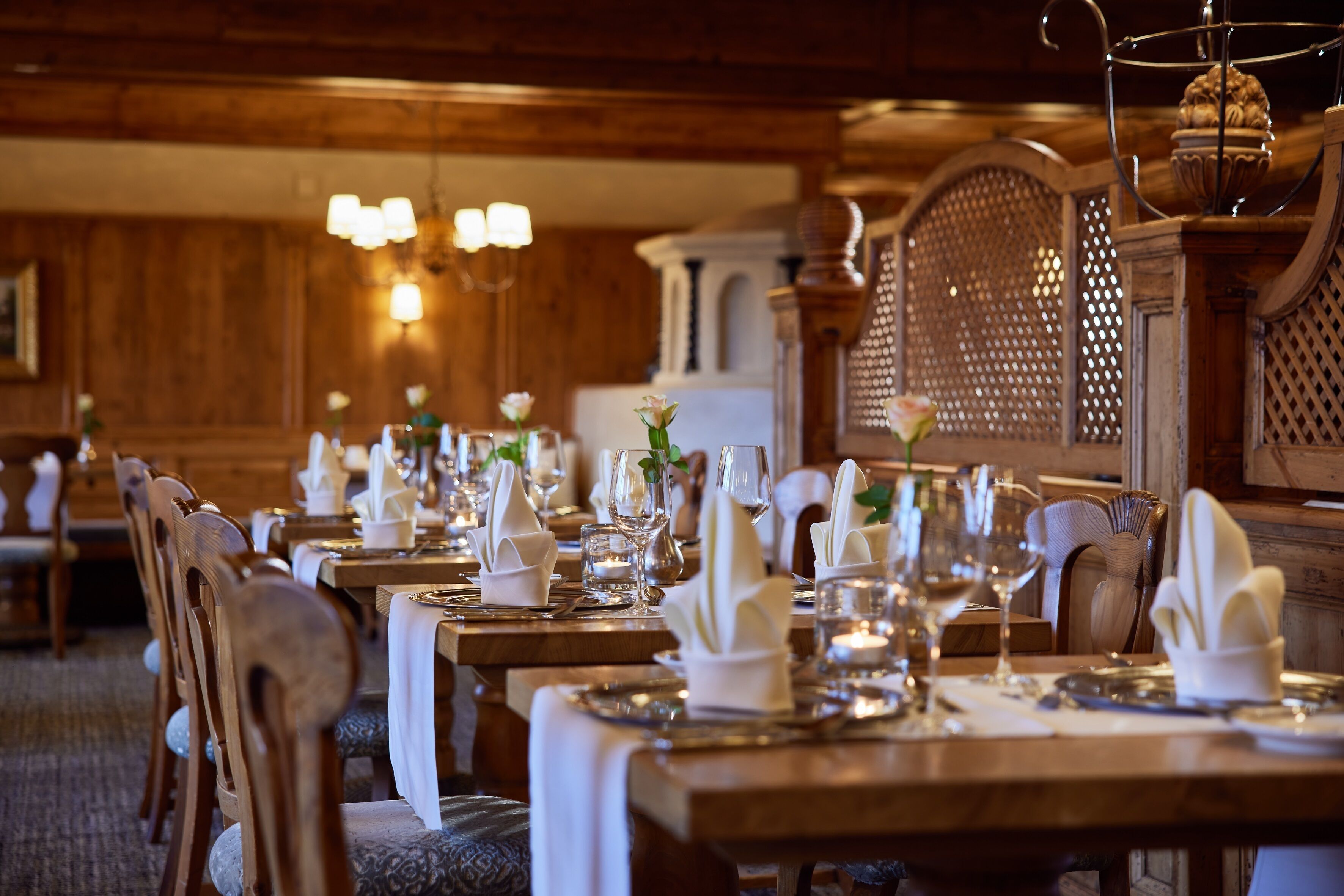 A restaurant with wooden tables set for dining, featuring white napkins and glassware.