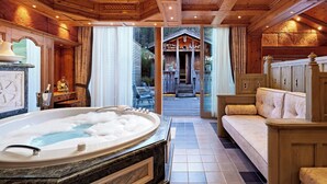 Een luxueuze badkamer met een groot bad, houten plafond en uitzicht op buiten.
