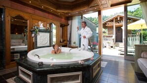 Een luxueuze badkamer met een ruime vrijstaand ligbad, een houten wastafelmeubel en een grote spiegel.
