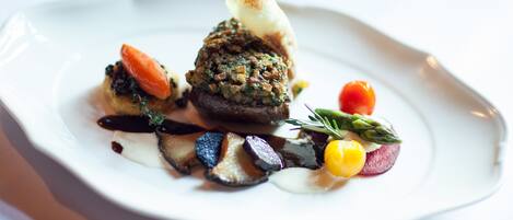 A white plate with a variety of food items including a mushroom, a piece of carrot, and some greens.