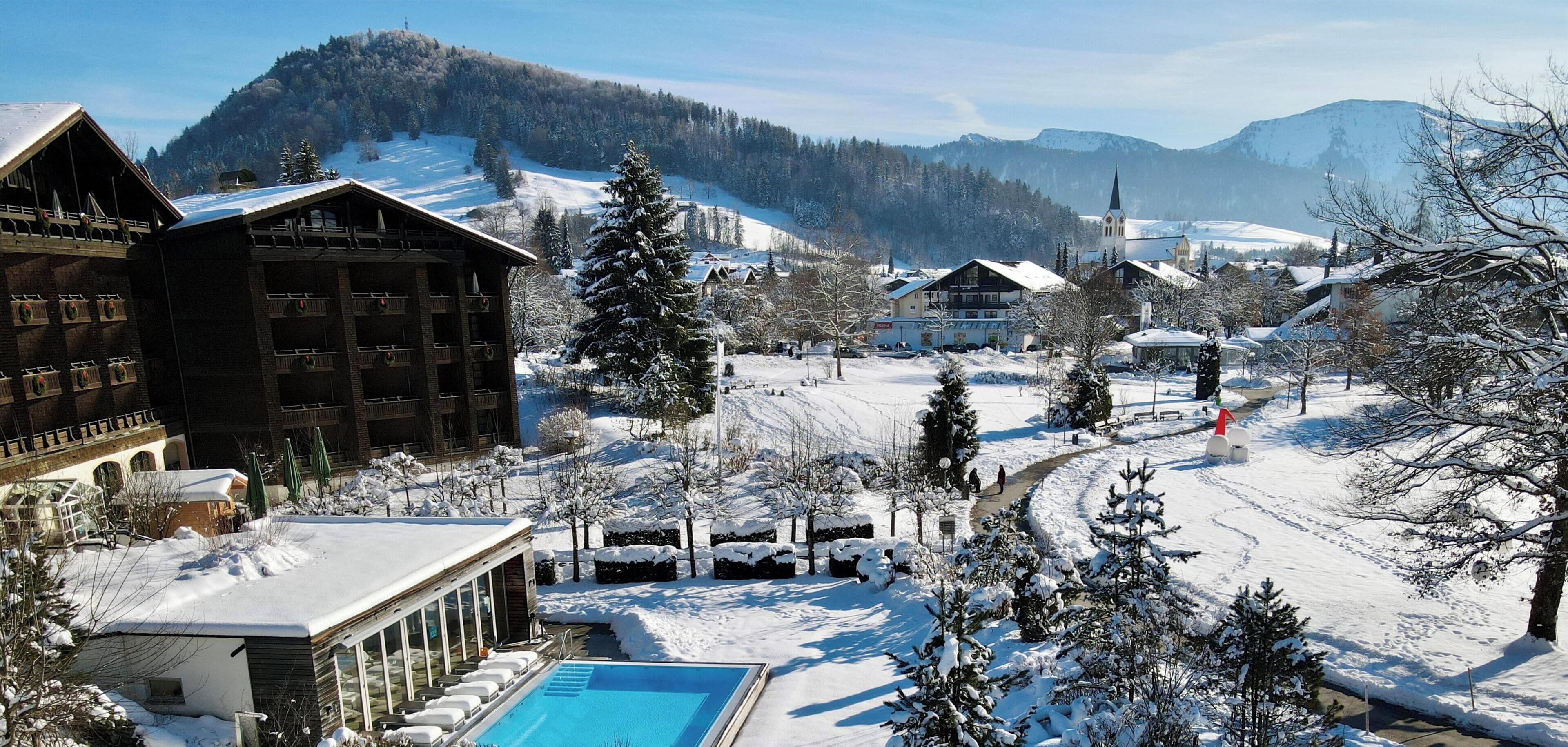A winter resort with a pool area, snow-covered landscape, and traditional chalet-style buildings.