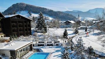 A winter resort with a pool area, snow-covered landscape, and traditional chalet-style buildings.