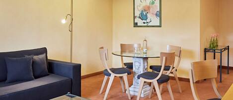Una sala de estar moderna con un sofá, una mesa de centro de vidrio, una mesa de comedor con sillas y una lámpara de pie.