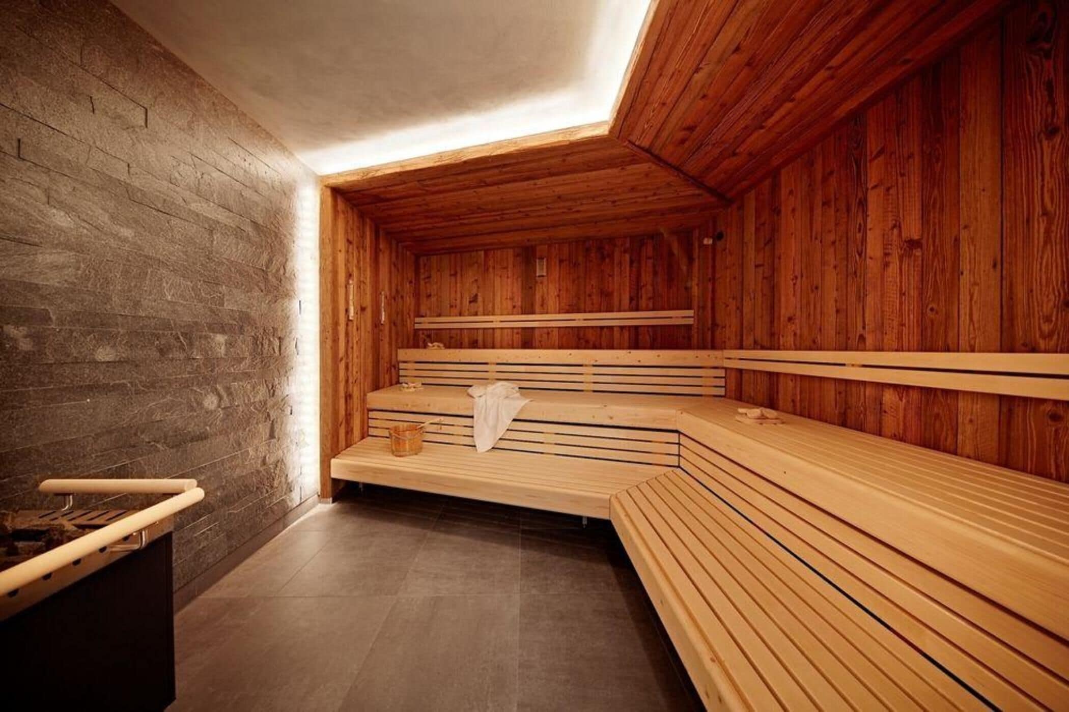 A sauna with wooden benches and a stone wall.