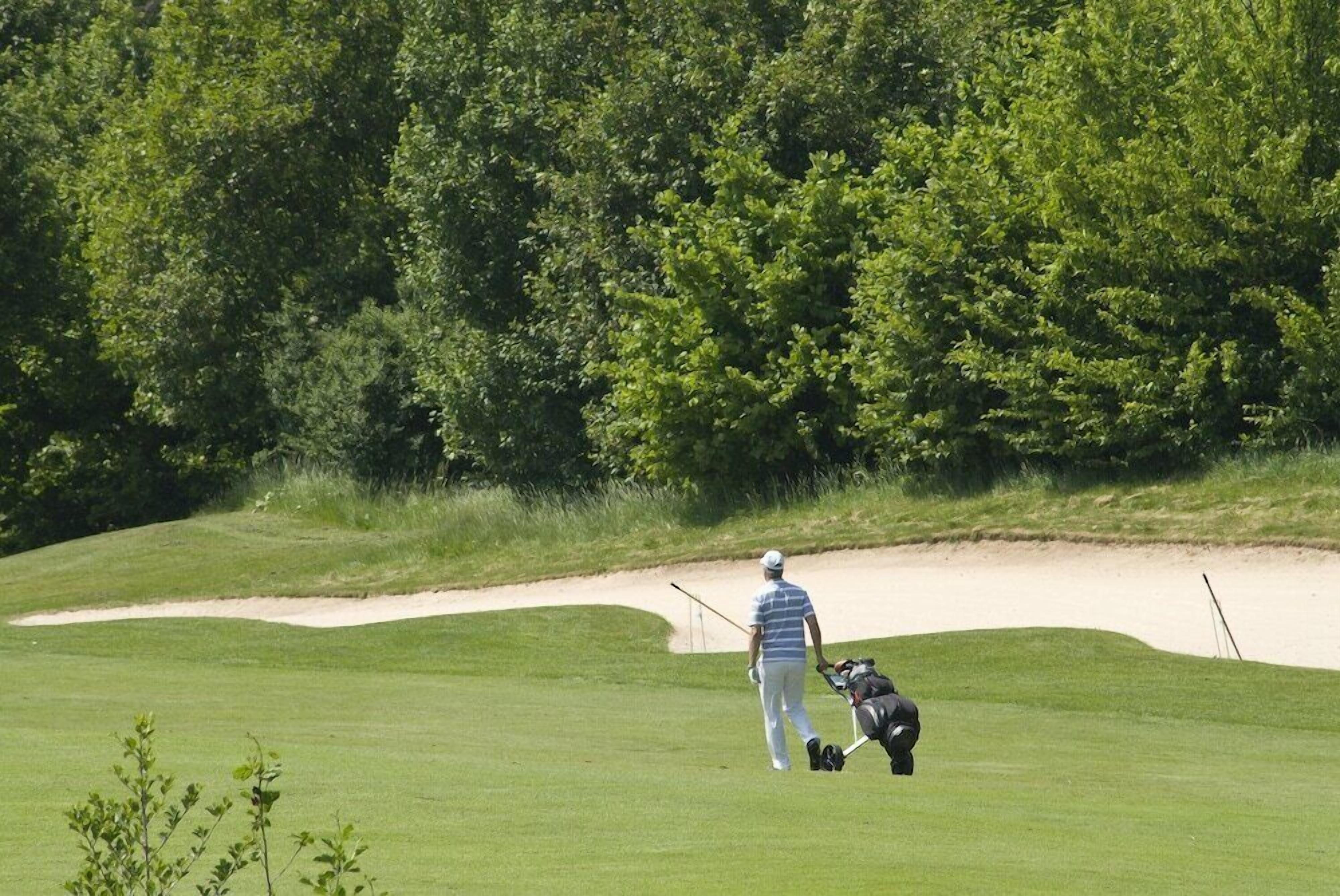 Un campo de golf con un jugador y su caddie.