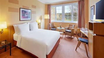 Une chambre d’hôtel avec un grand lit, deux chaises, une petite table et un téléviseur.